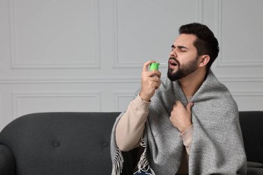 Genç adam içeride boğaz spreyi kullanıyor. Metin için boşluk