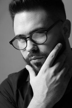 Gri arka planda sakallı yakışıklı bir adamın portresi. Siyah ve beyaz etkisi