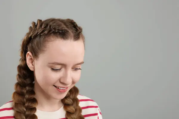 Woman with braided hair on grey background, space for text