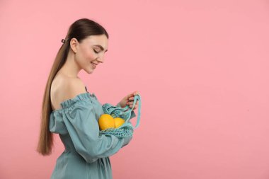 Pembe arka planda taze limon dolu bir torba kadın, mesaj için boşluk