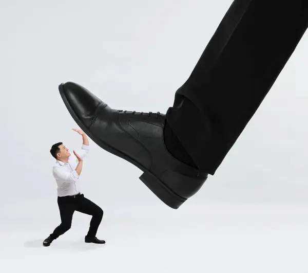 Giant stepping onto small man on white background
