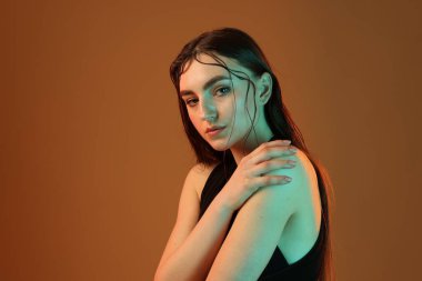 Kahverengi arka planda neon ışıklı güzel bir kadının portresi.