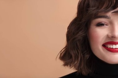 Bej arka planda dalgalı saç stili olan güzel bir genç kadın, yakın plan. Metin için boşluk