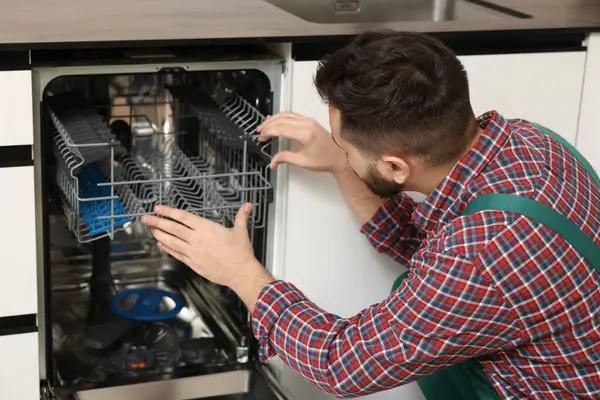 Serviceman repairing dishwasher cutlery rack indoors, closeup