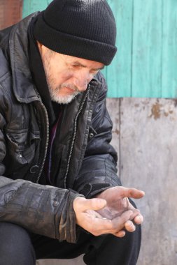 Zavallı evsiz yaşlı adam dışarıda bozuk para tutuyor.