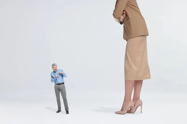 Giant woman and small man on light background