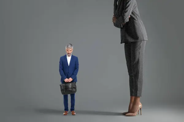 Giant woman and sad small man on grey background