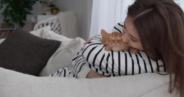女孩和她可爱的橙色小猫咪在家里的沙发上 — 图库视频影像
