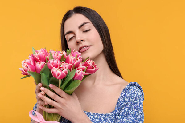 Счастливая молодая женщина с красивым букетом на оранжевом фоне