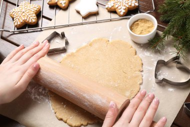 Noel kurabiyesi yapıyorum. Ahşap masada hamuru yuvarlayan kadın, yakın plan.
