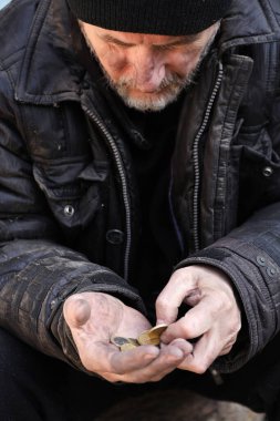 Zavallı evsiz yaşlı adam dışarıda bozuk para tutuyor.