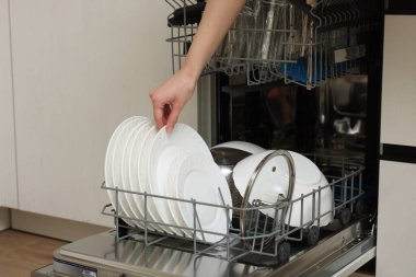 Bulaşık makinesini tabaklarla dolduran kadın, yakın plan.