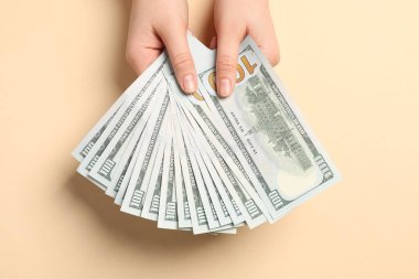 Para değişimi. Bej arka planda dolar banknotları tutan kadın, üst görünüm