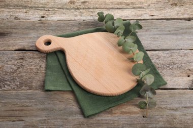 Kesme tahtası, okaliptüs dalı ve tahta masa peçetesi.