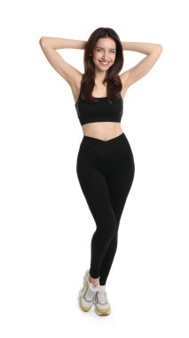 Beyaz arka planda poz veren zayıf vücutlu mutlu genç bir kadın.