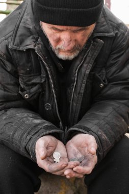 Zavallı evsiz yaşlı adam dışarıda bozuk para tutuyor.