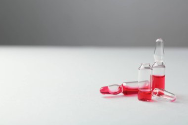 Beyaz zemin üzerinde sıvı bulunan cam ampuller. Metin için boşluk