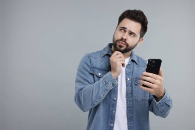 Gri arkaplanda akıllı telefon kullanan adam, metin için boşluk