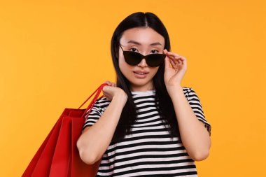 Sarı arka planda alışveriş torbaları olan güzel bir kadın.