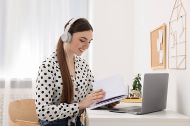E-öğrenme. İçerideki masada online ders sırasında dizüstü bilgisayar kullanan genç bir kadın.
