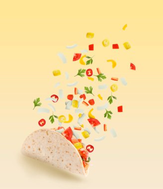 Turuncu arka planda uçan malzemeli lezzetli taco.