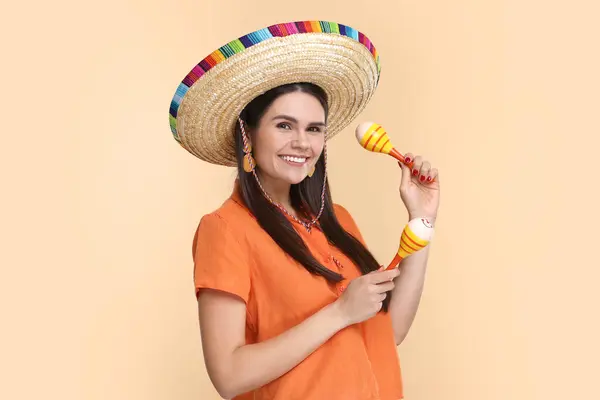 stock image Young woman in Mexican sombrero hat with maracas on beige background