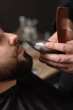 Berber dükkanında müşterinin bıyığını kesen profesyonel berber.