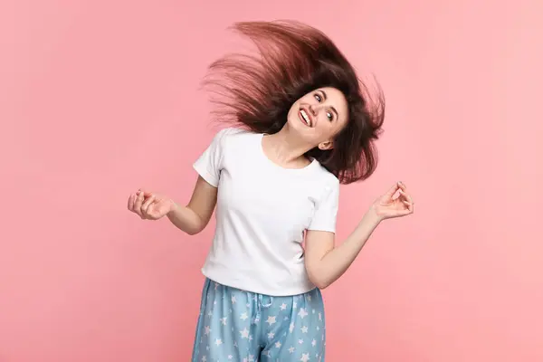 Happy woman in pyjama shaking head on pink background