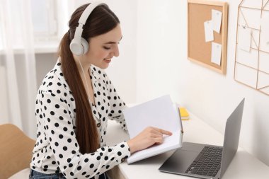 E-öğrenme. İçerideki masada online ders sırasında dizüstü bilgisayar kullanan genç bir kadın.