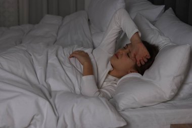 Küçük kız gece yatağında baş ağrısı çekiyor.