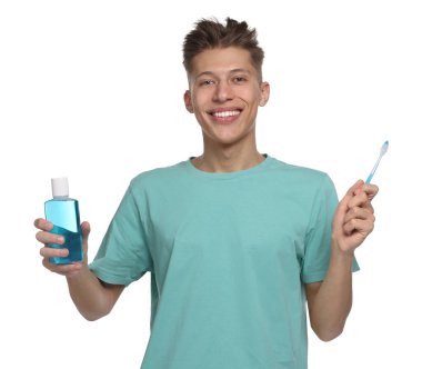 Beyaz arka planda diş fırçası ve gargarası olan genç bir adam.