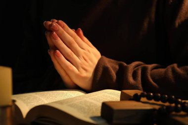 İncili olan kadın masada dua ediyor, yakın plan.