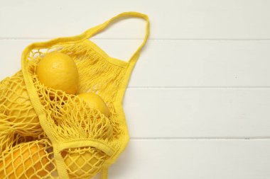 Beyaz ahşap arka planda taze limonlu ip torbası, üst manzara. Metin için boşluk