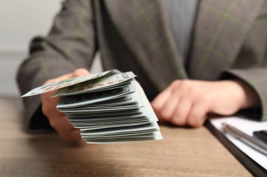 Para değişimi. Tahta masada elinde dolar banknotları tutan kadın, yakın plan.