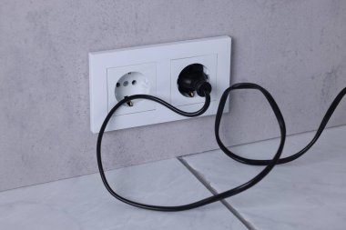 Gri duvarda elektrik prizi ve prizler var.