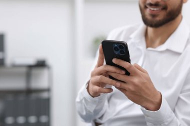 Ofiste akıllı telefon kullanan genç adam, yakın plan. Metin için boşluk