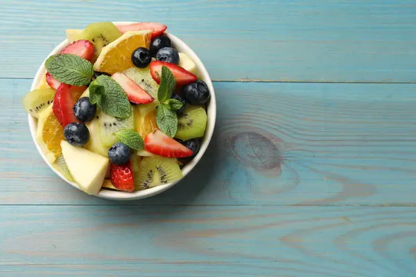 Tasty Fruit Salad Bowl Light Blue Wooden Table Top View — Stock Photo, Image