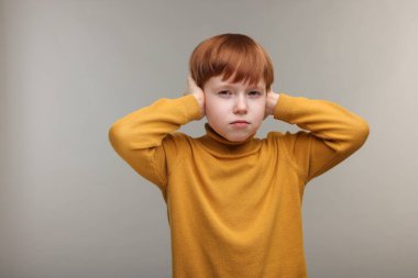 İşitme problemi. Küçük çocuk gri arka planda kulak ağrısından muzdarip, mesaj için boşluk