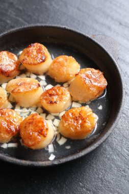 Koyu gri desenli masada, tabakta nefis kızarmış deniz tarakları.