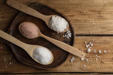 Tahta masadaki kaşıklardaki farklı doğal tuz, düz. Metin için boşluk