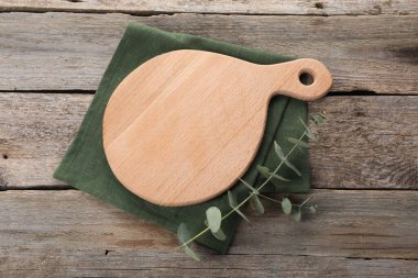 Kesme tahtası, okaliptüs dalı ve tahta masa üzerindeki peçete.