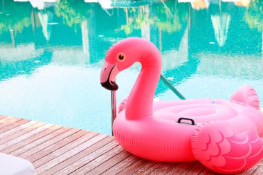 Lüks bir tatil köyünde yüzme havuzunun yanındaki tahta güvertede flamingo şeklinde süzül.