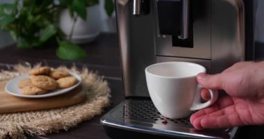 Adam, modern espresso makinesiyle taze aromatik kahve hazırlıyor mutfaktaki siyah ahşap tezgahta, yakın plan.