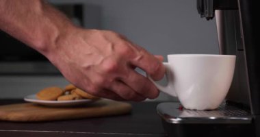 Adam, modern espresso makinesiyle taze aromatik kahve hazırlıyor mutfaktaki siyah ahşap tezgahta, yakın plan.