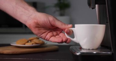 Adam, modern espresso makinesiyle taze aromatik kahve hazırlıyor mutfaktaki siyah ahşap tezgahta, yakın plan.