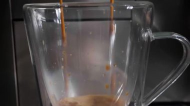 Modern kahve makinesi cam fincana espresso yapıyor, yakın plan.