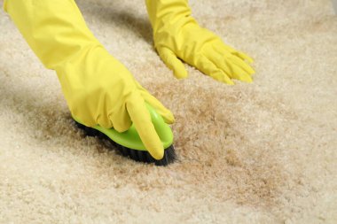 Bej halıdaki lekeyi çıkaran kadın, yakın plan.