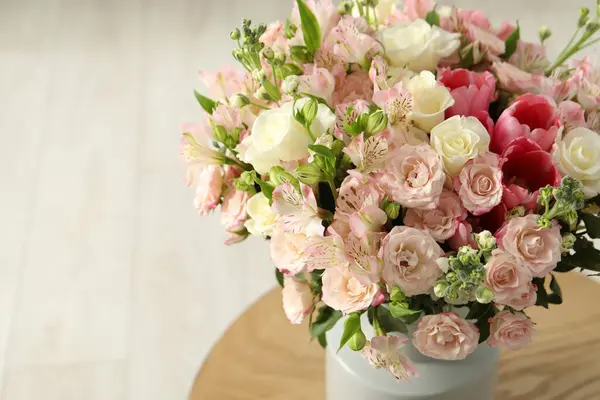 Beautiful bouquet of fresh flowers in vase on wooden table, space for text