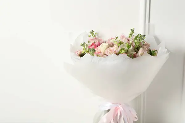 Beautiful bouquet of fresh flowers near white wall, space for text