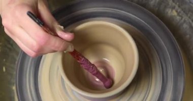 Potter kil vazoyu fırlatma çarkında dekore ediyor, yakın plan. Seramik sanat
